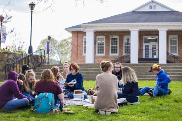 a group of people sitting on the grass in front of a building